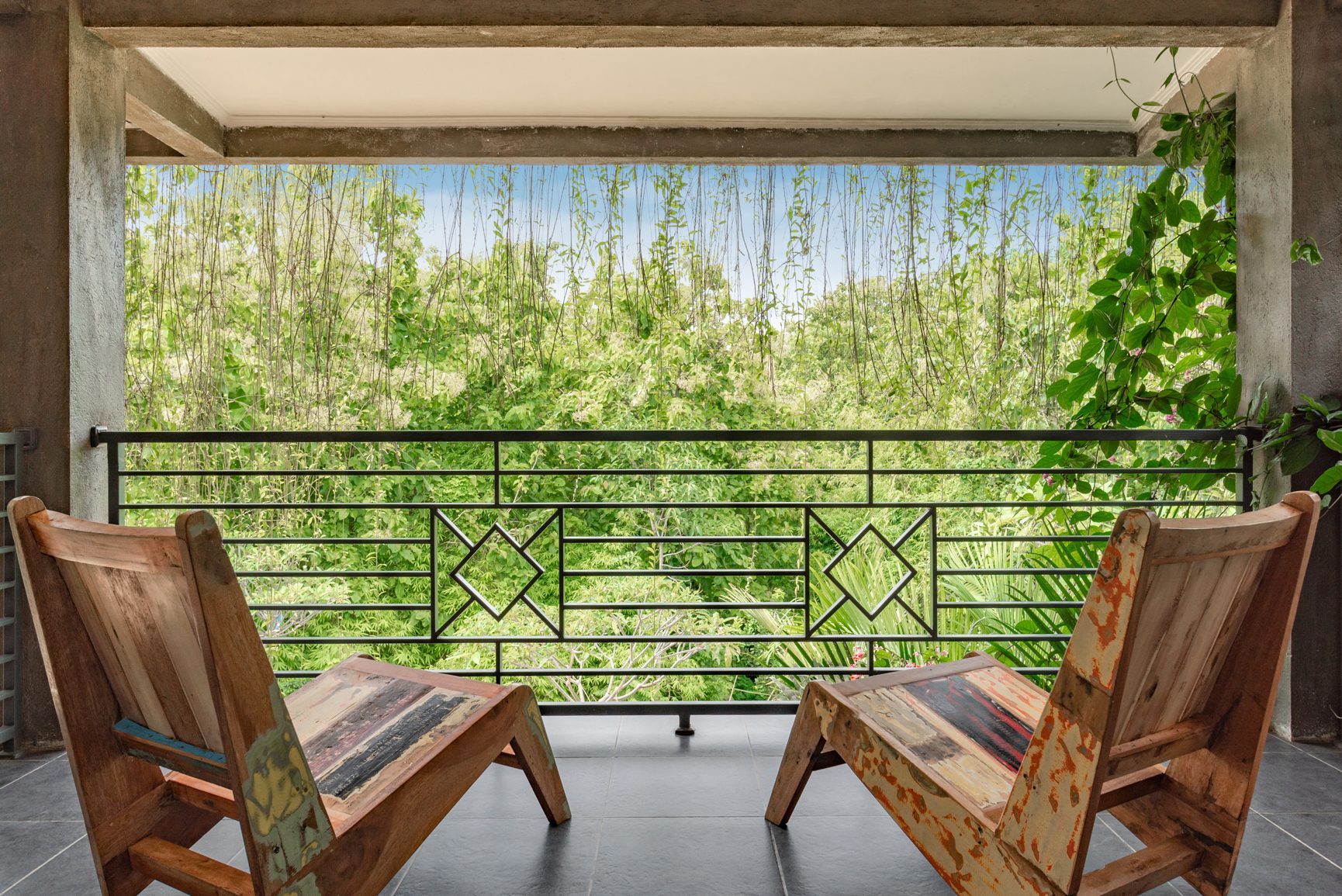 Timber chairs on a room balcony at Alamanda looking into dense green jungle