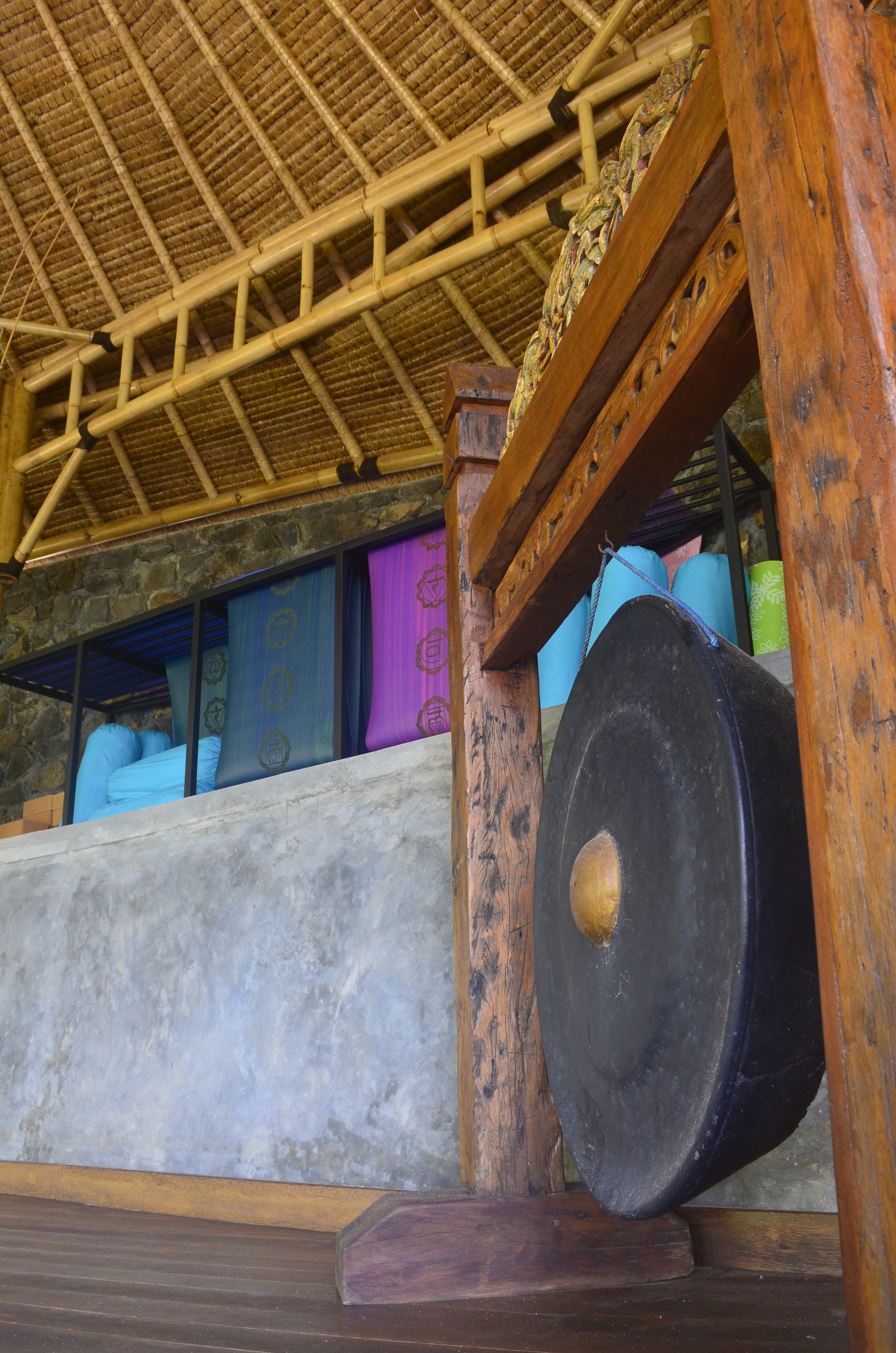 Sound healing gong beside rolled yoga mats in the Shala